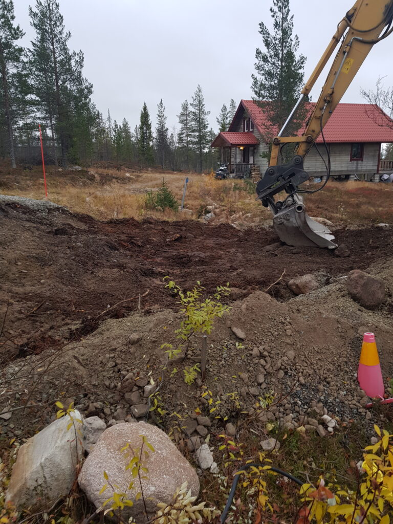 Avtäcker marken och jämnar ut det med grävmaskin för öppen plintgrund Avtäcker marken och jämnar ut det med grävmaskin för öppen plintgrund