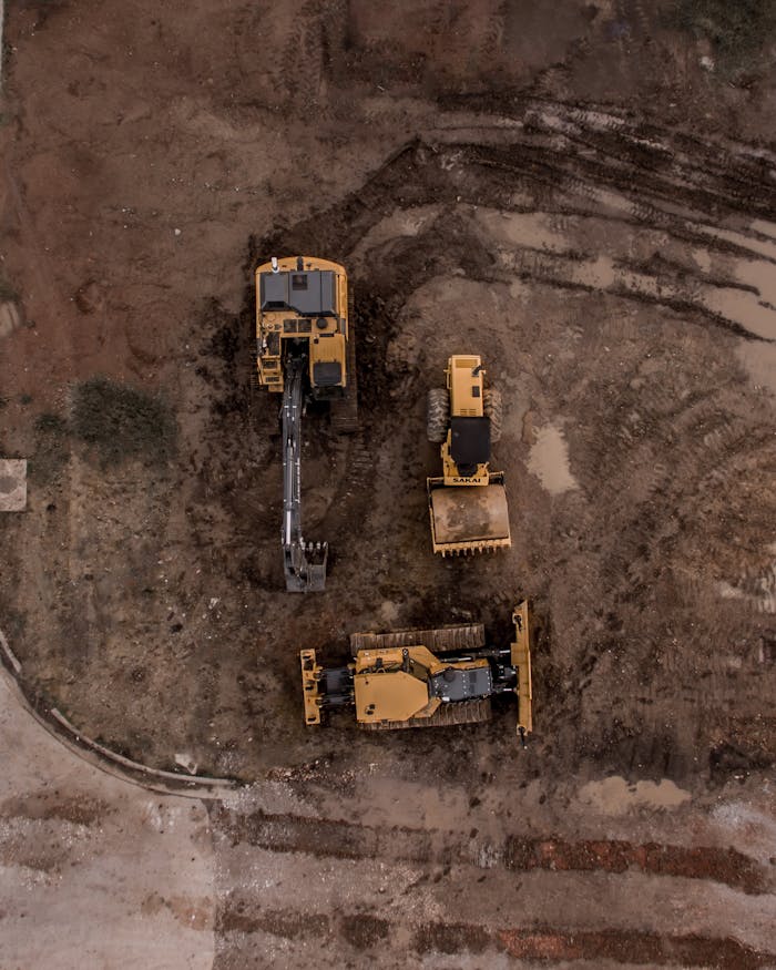 our-story An aerial shot of heavy machinery at a construction site, including excavators and road rollers.